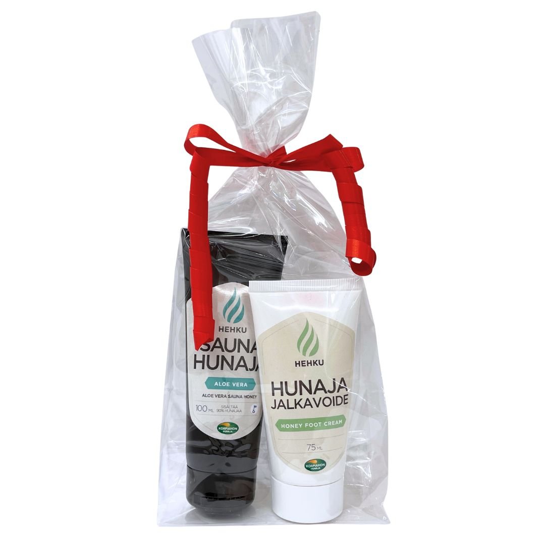 Sellofaaniin punaisella lahjanarulla pakattu lahjasetti, jossa aloe-vera saunahunaja ja hunaja-jalkavoide