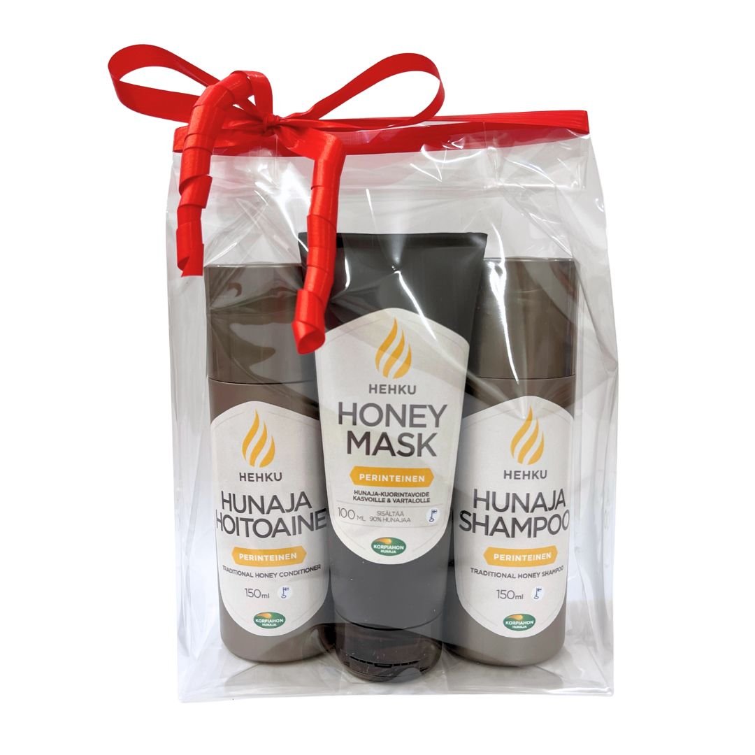 Sellofaanipussiin punaisella lahjanarulla pakatut hunajaiset shampoo, hoitoaine ja kuorintavoide