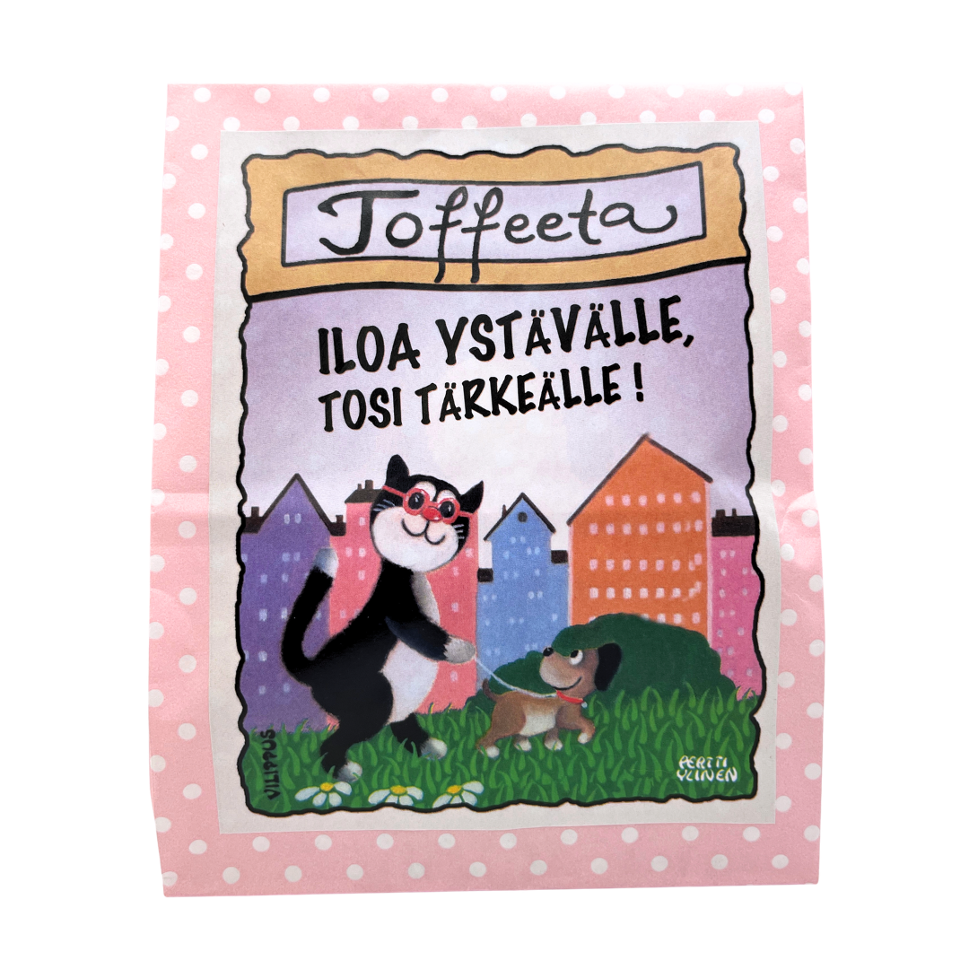 Kermatoffee vaaleanpunaisessa paperipussissa, jonka etiketissä kuvitus koiraa ulkoiluttavasta kissasta, sekä teksti "Iloa ystävälle, tosi tärkeälle!"